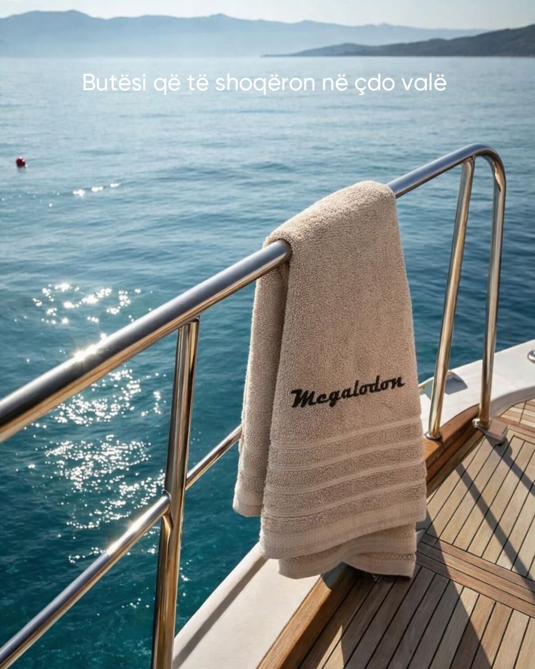 A Megalodon-embroidered towel resting on the rail above the sea